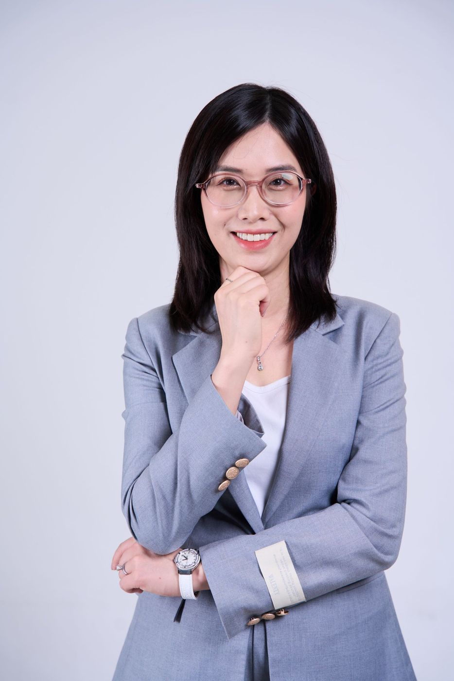 Chloe Le smiling, wearing glasses and a gray blazer